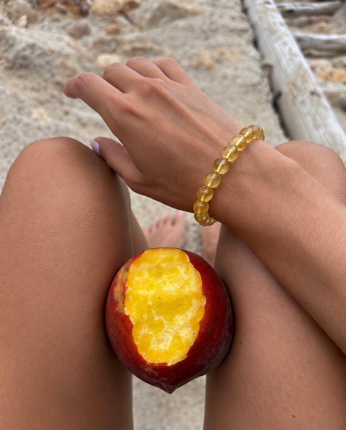 A yellow gemstone bead bracelet worn on the wrist at the beach